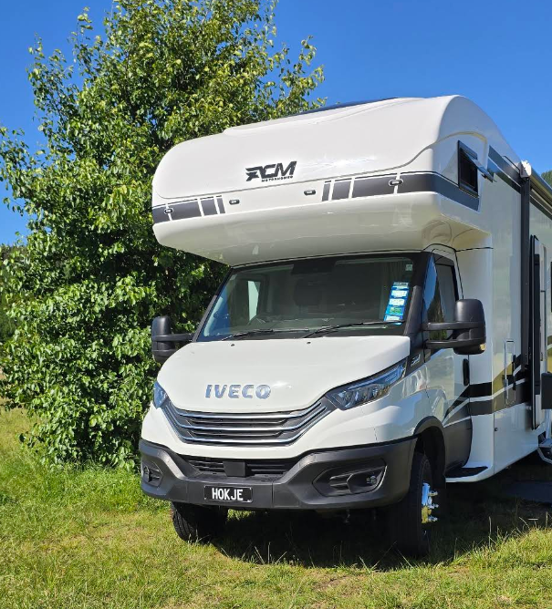 acm motorhome parked on grass with a blue sky